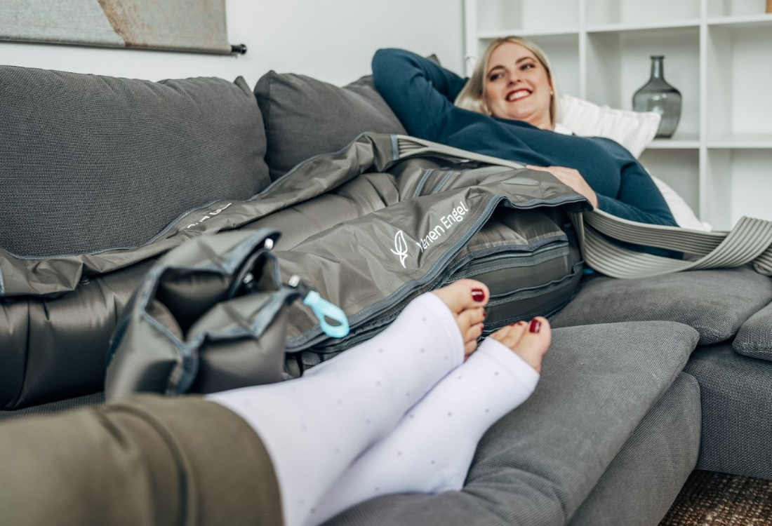 Venen Engel: Frau lächelnd auf Sofa mit Kompressionssocken