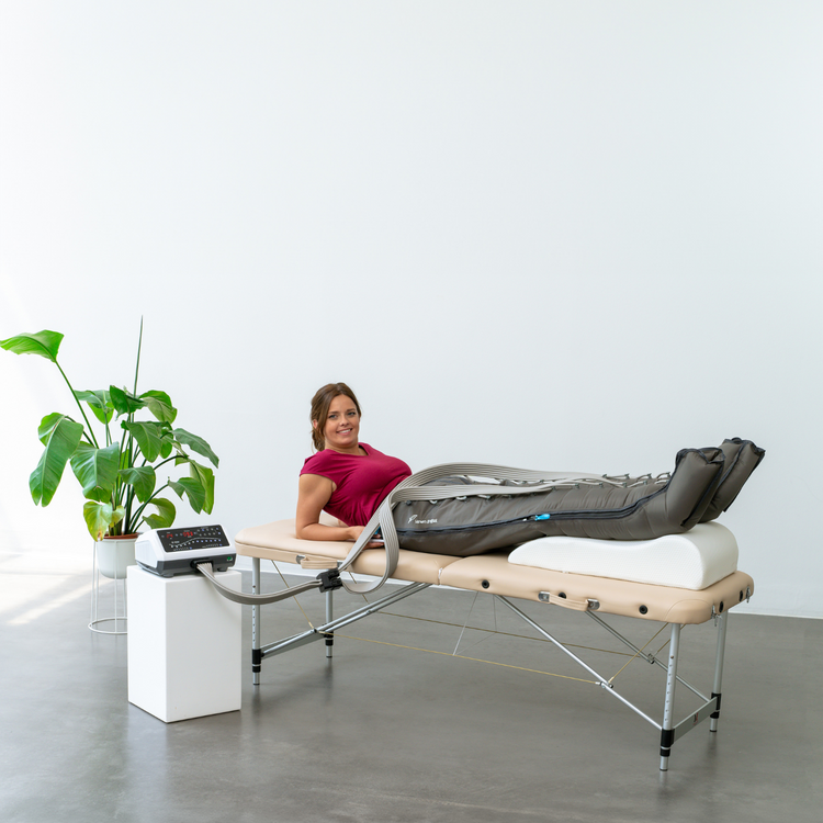 Venen Engel: Frau auf Liege mit Armen gestützt und Massagegerät an den Beinen