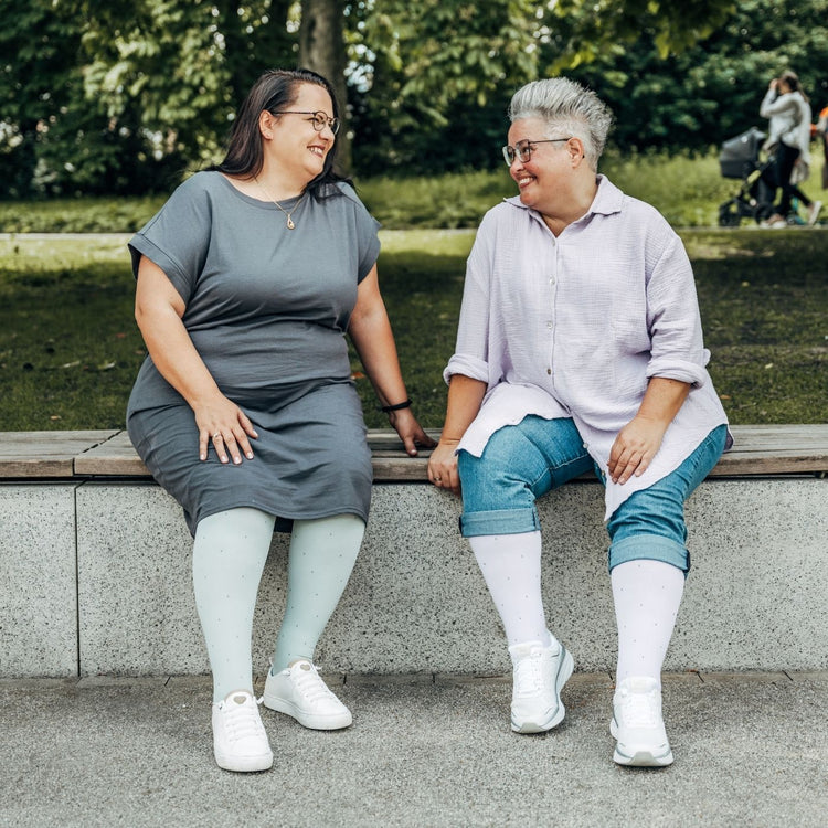 Venen Engel: 2 Frauen sitzen auf Parkmauer mit Kompressionssocken