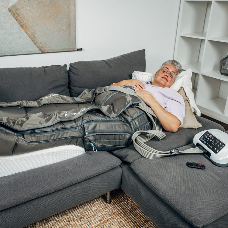 Venen Engel: Frau mit kurzen Haaren liegt entspannt auf Sofa mit Kompressionsmassagegerät
