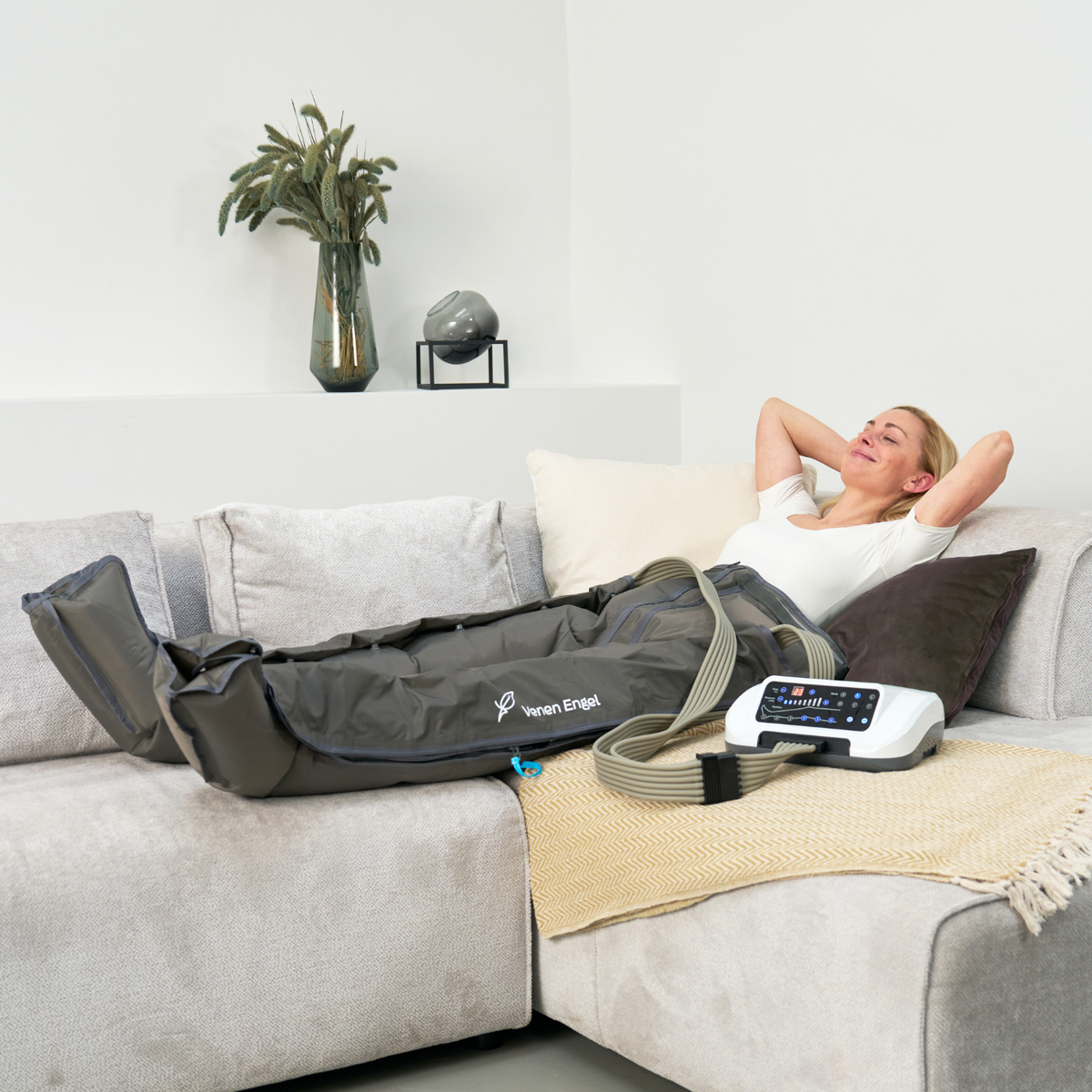 Venen Engel: moodbild frau auf sofa mit kompressionsmassagegerät an bein
