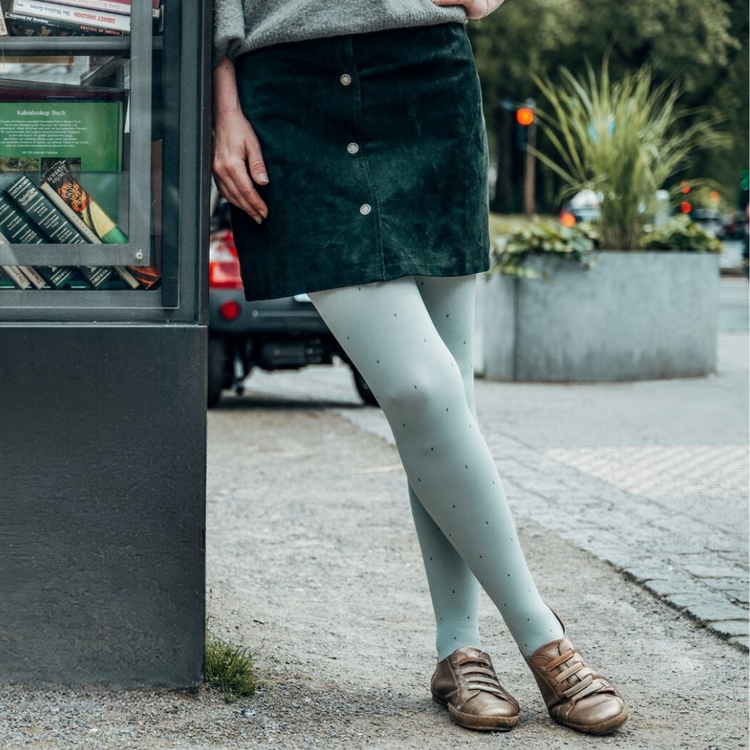 Venen Engel: Frau lehnt an mobiler Buchsäule mit Kompressionssocken an Beinen