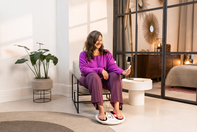 Venen Engel: Frau glücklich in lila Homewear und Füße auf EMS Venen Board