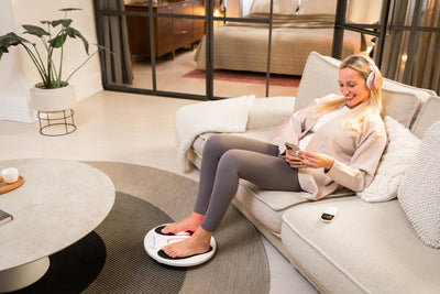 Venen Engel: Frau mit Handy auf Sofa und EMS Venen Board